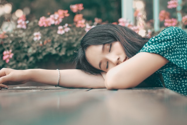 woman with her head down trying to get your sleep schedule back on track