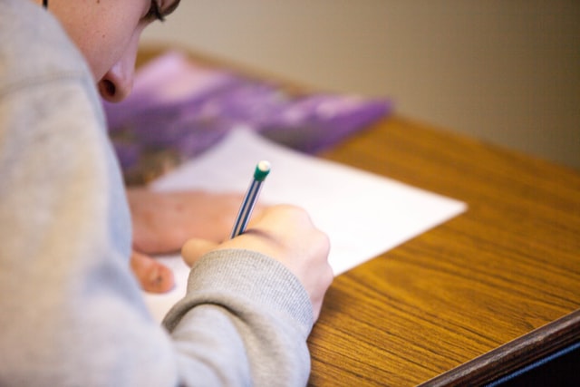 woman at a desk with pencil feeling anxiety with test taking