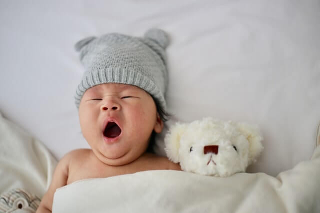 new mom anxiety with a newborn baby wearing a hat and yawning