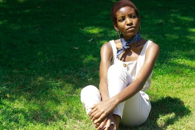 young adult woman sitting on grass overthinking after social interactions