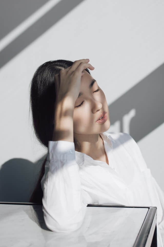 young adult asian woman sitting at desk with social anxiety overthinking conversations