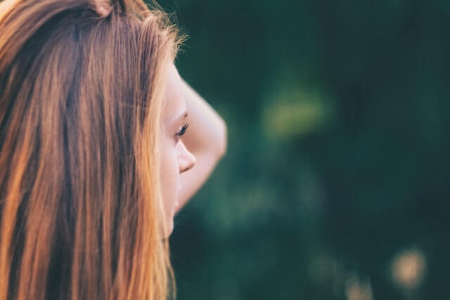 Anxious young adult woman with hand on her head.