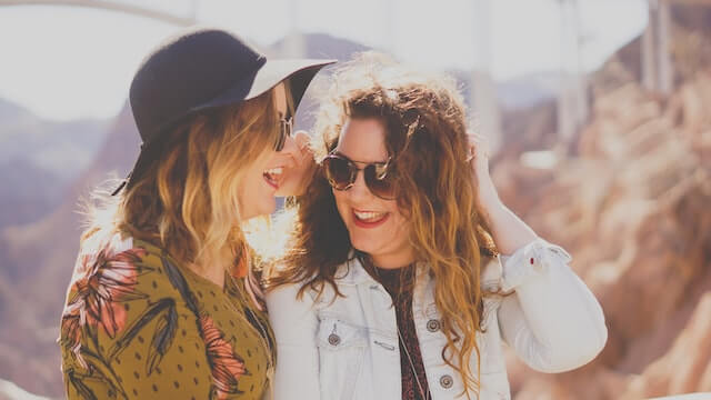 Two young adult women friends outside with sunglasses in New York talking.