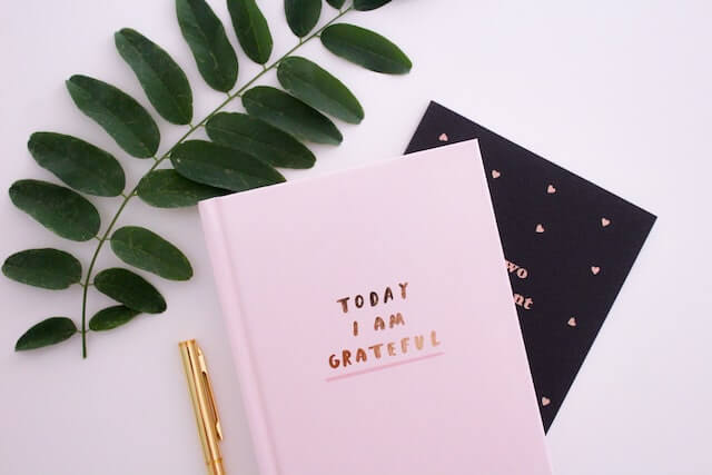 pink notebook with the writing of grateful on the cover to show an attitude of gratitude meaning