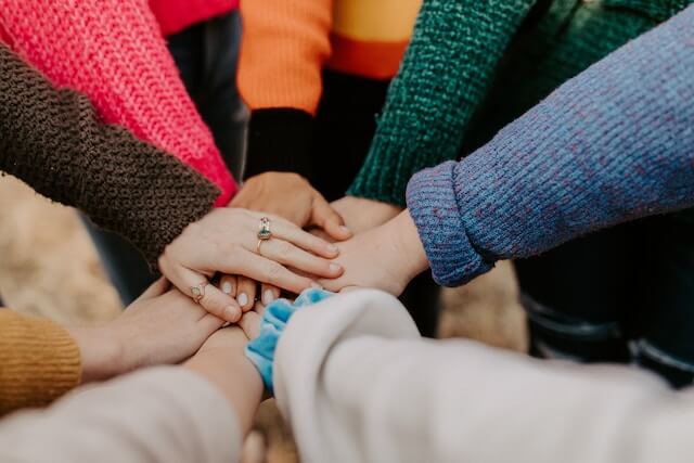 Young adult women touching hands in a circle 