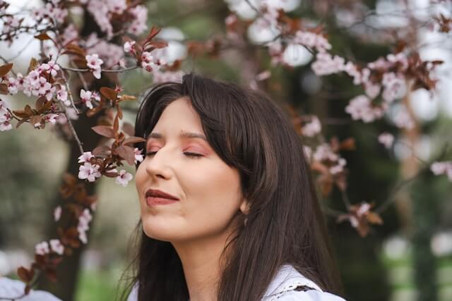 Young adult woman smelling flowers and staying present to stop anticipatory anxiety
