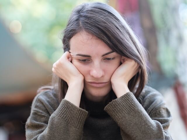 Young adult woman with head in her hands anticipatory anxiety